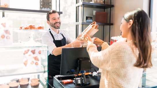 Mann reicht einer Frau Brot beim Bäcker Mann reicht einer Frau Brot beim Bäcker